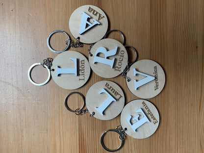 Colección de llaveros de madera con diferentes iniciales grabadas, destacando la personalización y la calidad del acabado.