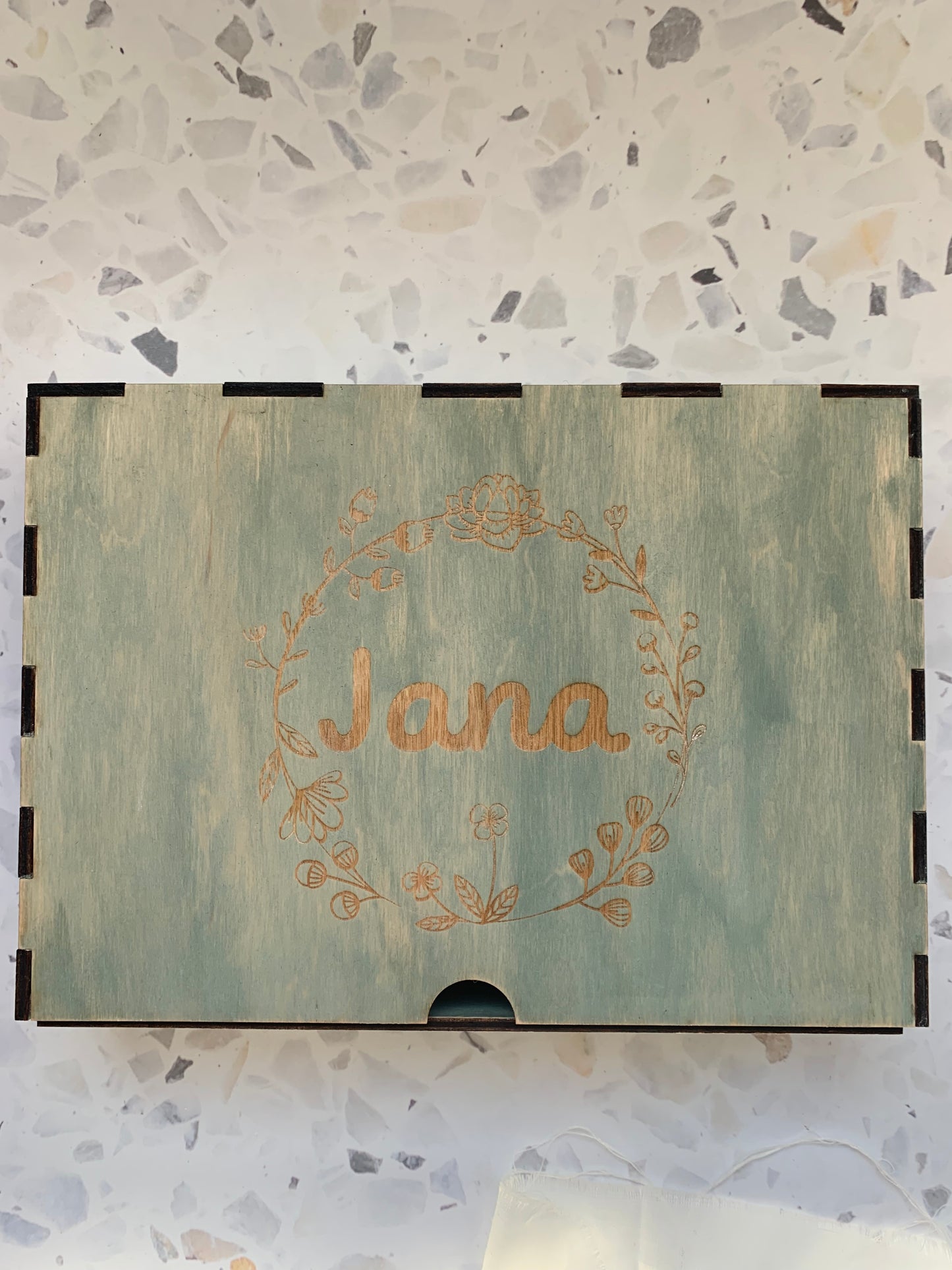 Cajón de madera personalizado para recuerdos, colocado en un ambiente acogedor, resaltando la calidad del grabado y la madera.