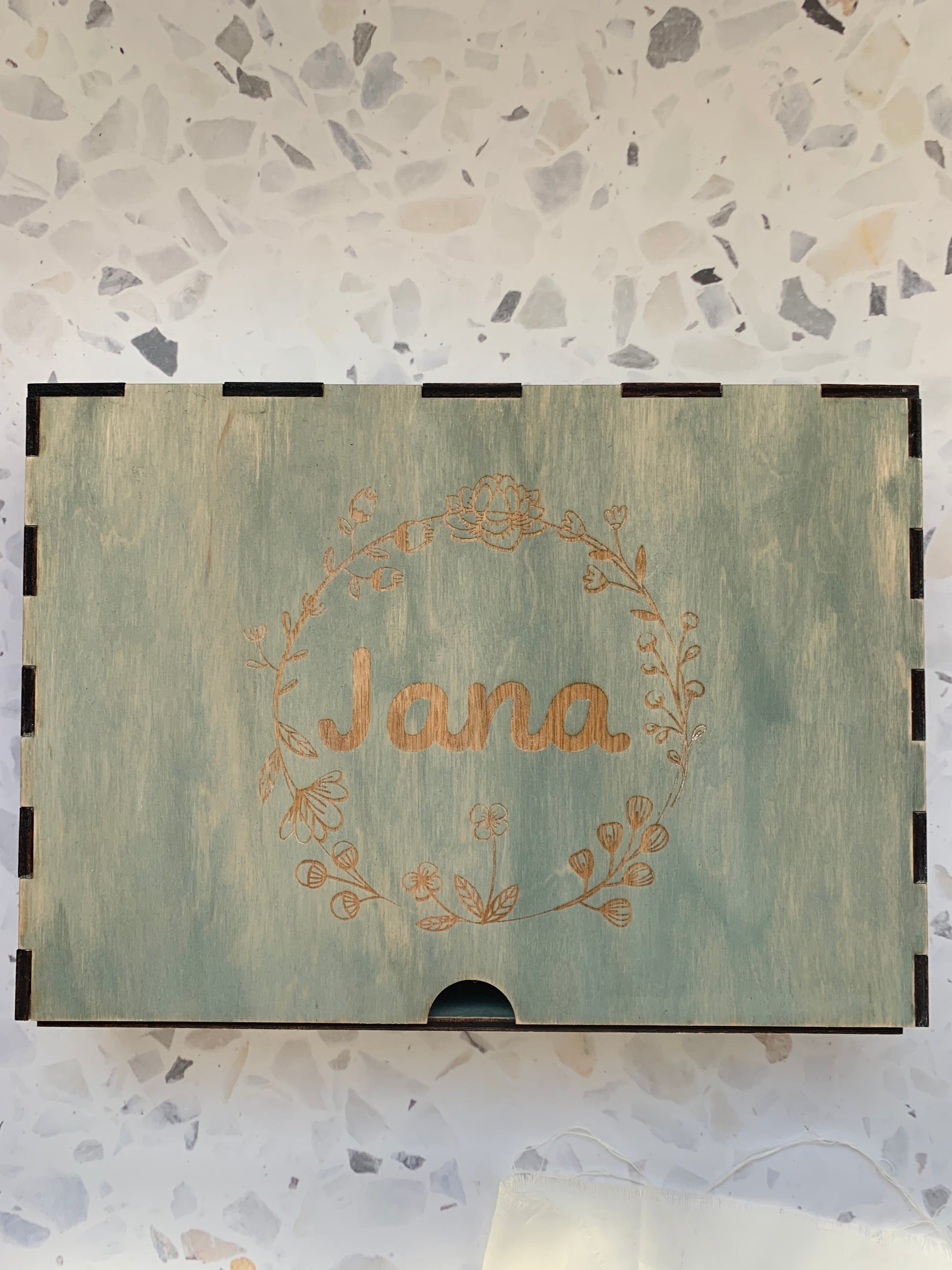 Cajón de madera personalizado para recuerdos, colocado en un ambiente acogedor, resaltando la calidad del grabado y la madera.