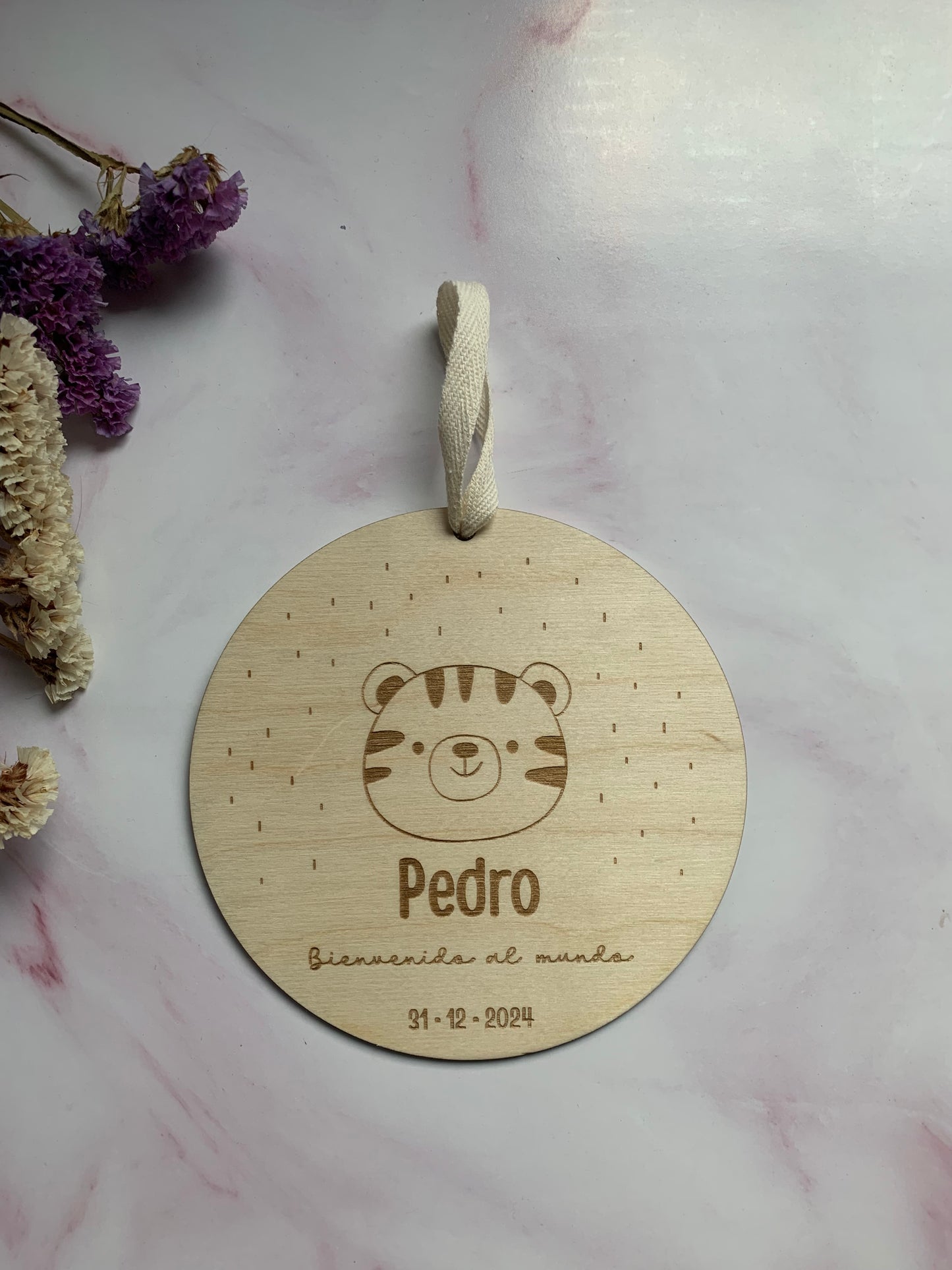 Detalle del grabado personalizado en la placa de nacimiento de madera, mostrando la calidad del texto y números.