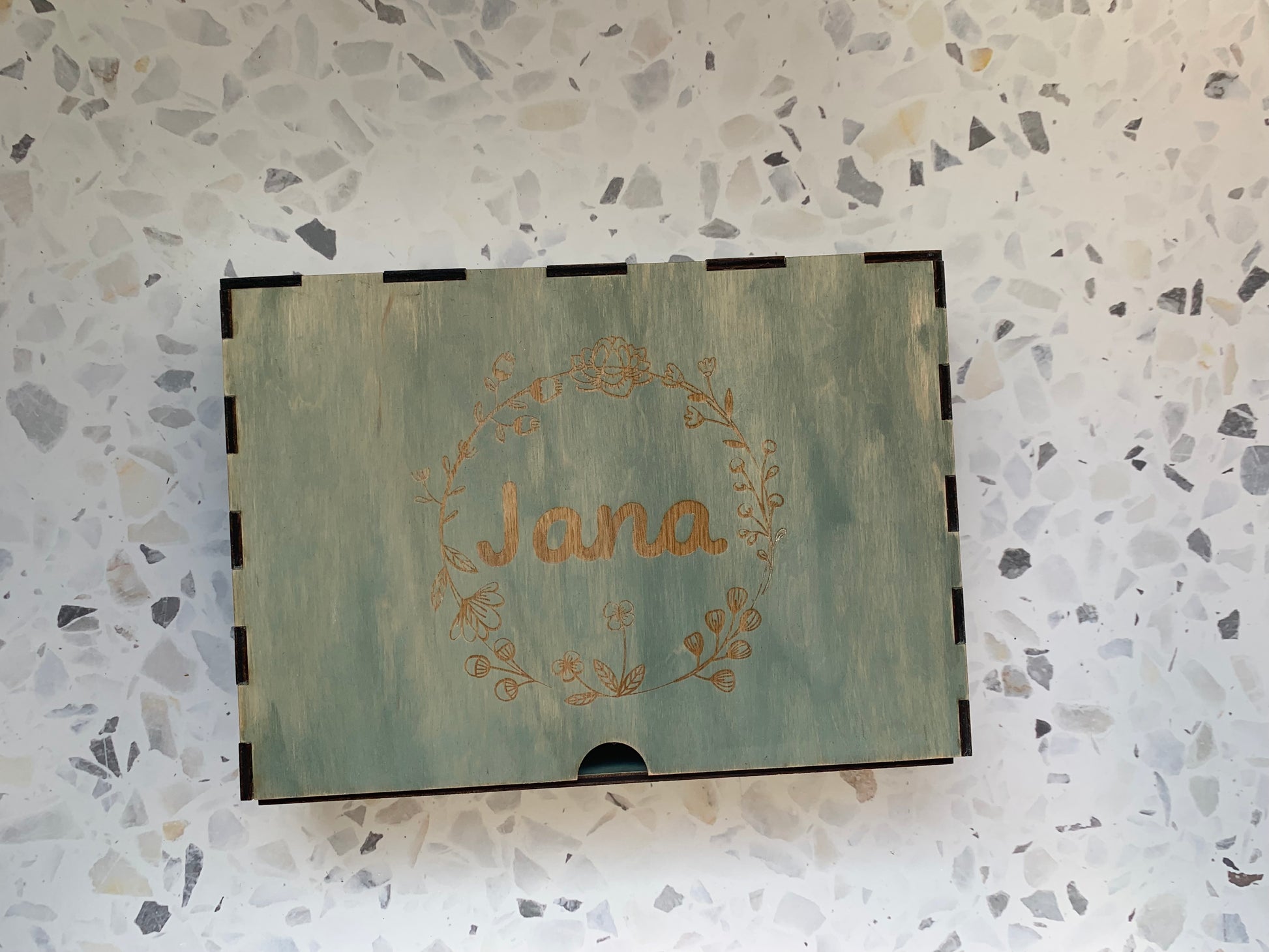 Cajón de madera personalizado para recuerdos, colocado en un ambiente acogedor, resaltando la calidad del grabado y la madera.