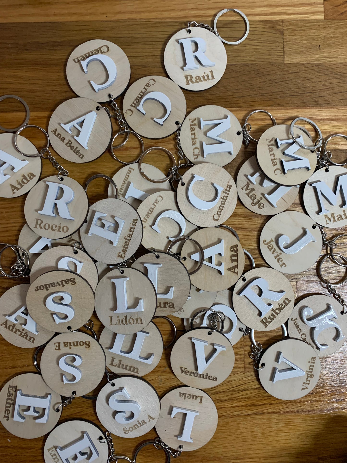 Colección de llaveros de madera con diferentes iniciales grabadas, destacando la personalización y la calidad del acabado.