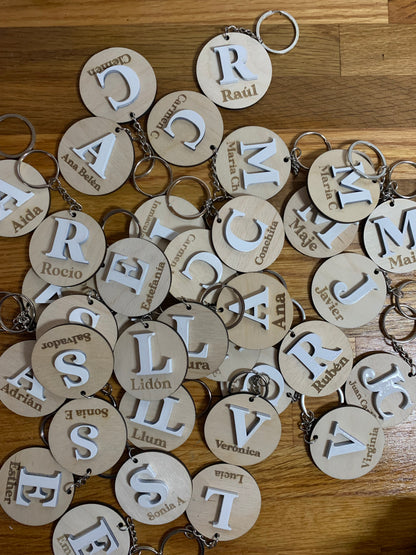 Colección de llaveros de madera con diferentes iniciales grabadas, destacando la personalización y la calidad del acabado.