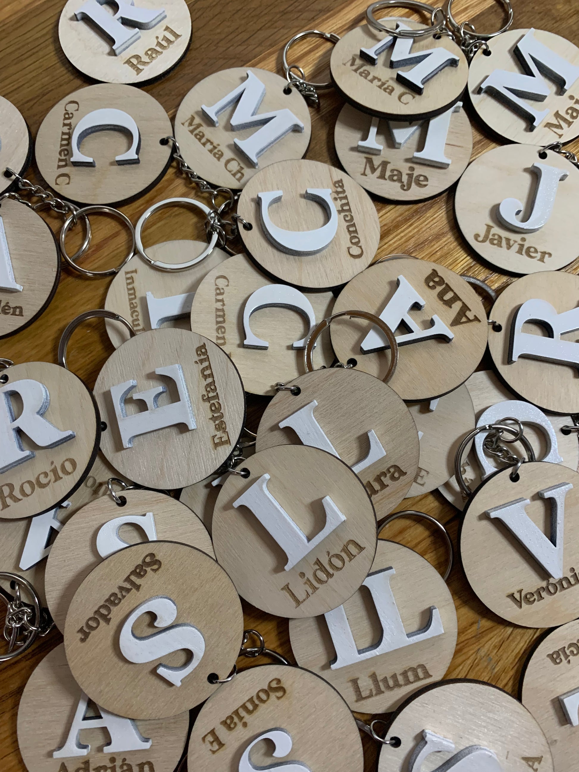 Colección de llaveros de madera con diferentes iniciales grabadas, destacando la personalización y la calidad del acabado.