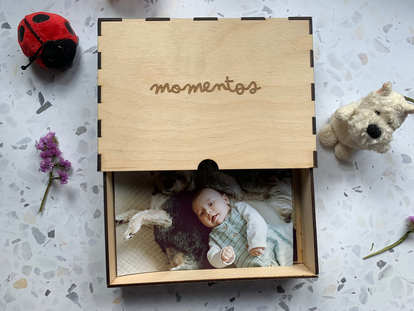 Cajón de madera para recuerdos abierto, revelando su interior y sugerencias de objetos personales como fotos o chupetes.