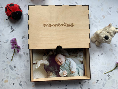 Cajón de madera para recuerdos abierto, revelando su interior y sugerencias de objetos personales como fotos o chupetes.