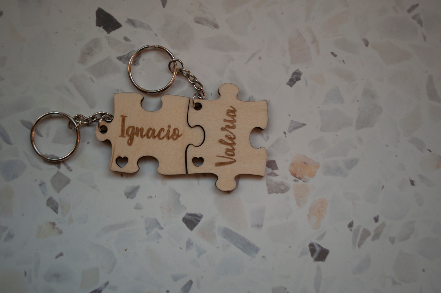 Dos piezas separadas de un llavero puzzle de madera personalizado, mostrando los detalles del grabado del nombre y el diseño único.