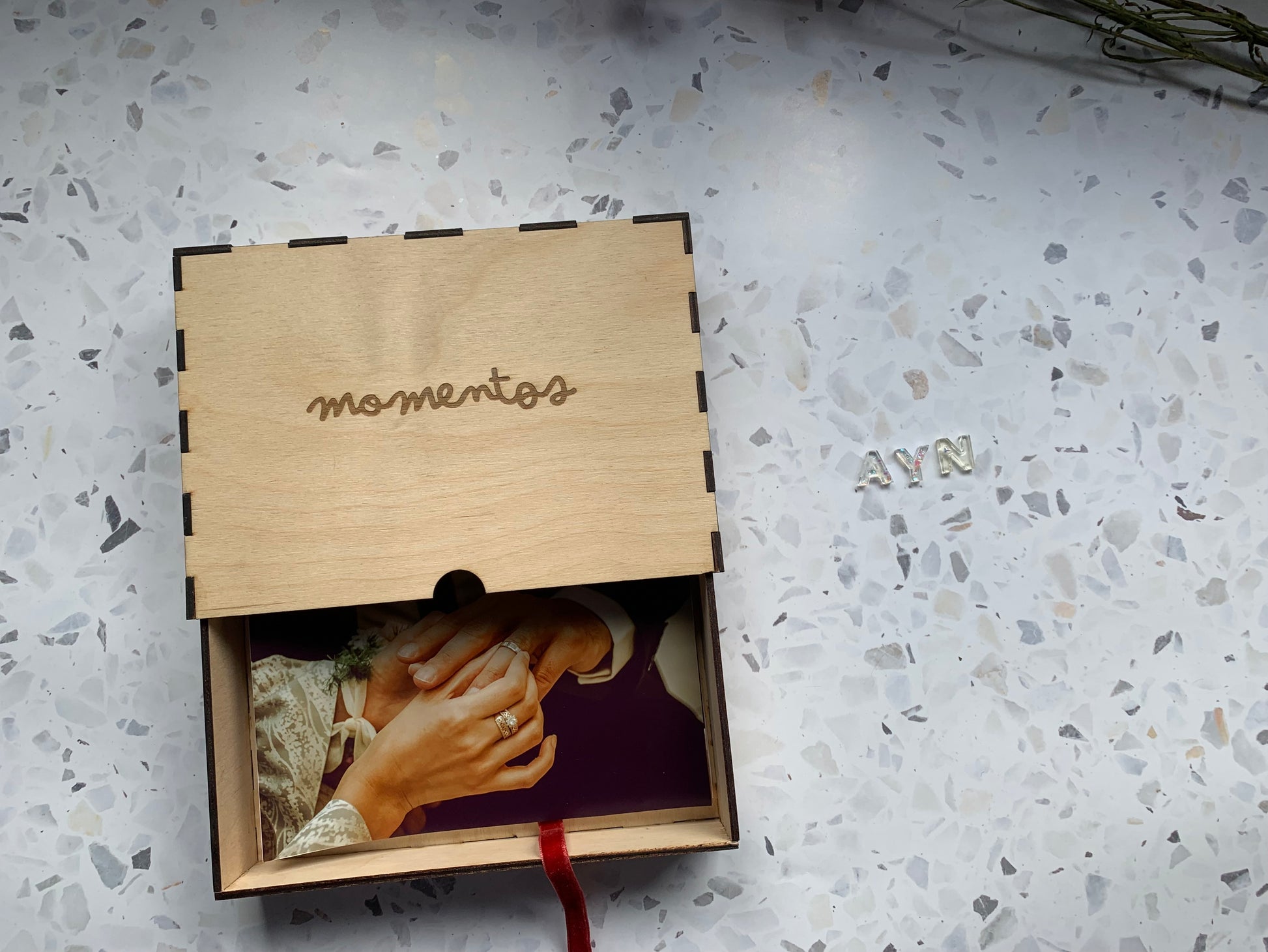 Cajón de madera para recuerdos abierto, revelando su interior y sugerencias de objetos personales como fotos o chupetes.