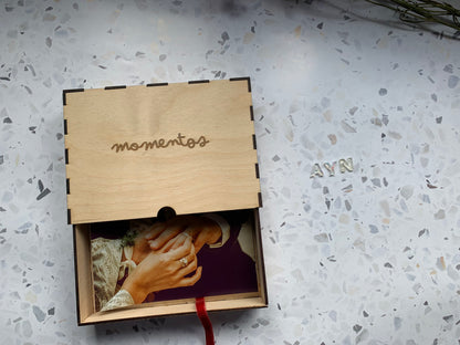 Cajón de madera para recuerdos abierto, revelando su interior y sugerencias de objetos personales como fotos o chupetes.